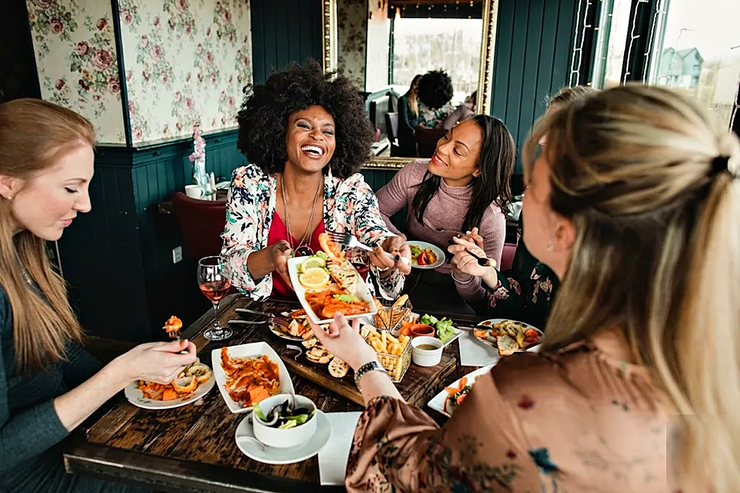 Friends laughing over a shared meal at a restaurant.
